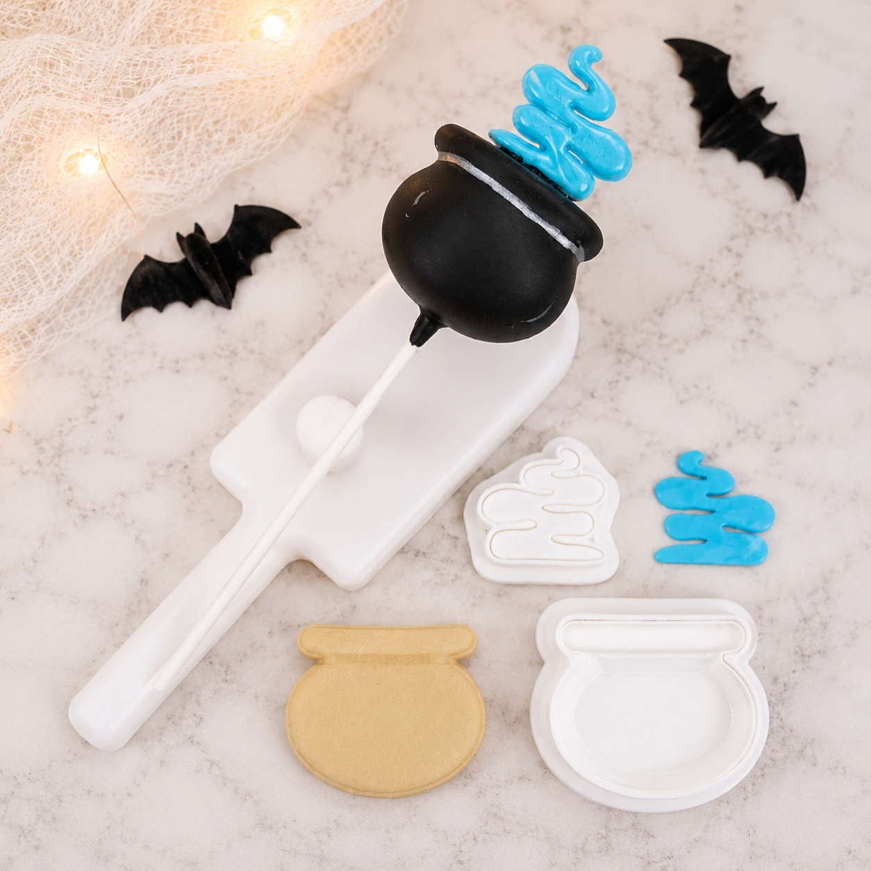 A Halloween-themed cake pop cutter. The set includes a cauldron cake pop cutter and plunger with a fondant cutter for the smoke