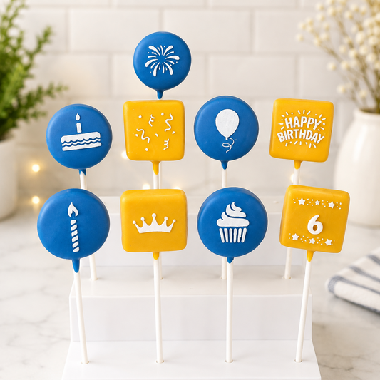 A set of blue and yellow birthday cake pops, displayed on a white stand. The cake pops include designs for a birthday cake, candle, balloon, cupcake, crown, fireworks, and a 'HAPPY BIRTHDAY' sign. Showing out Birthday stencils in use.